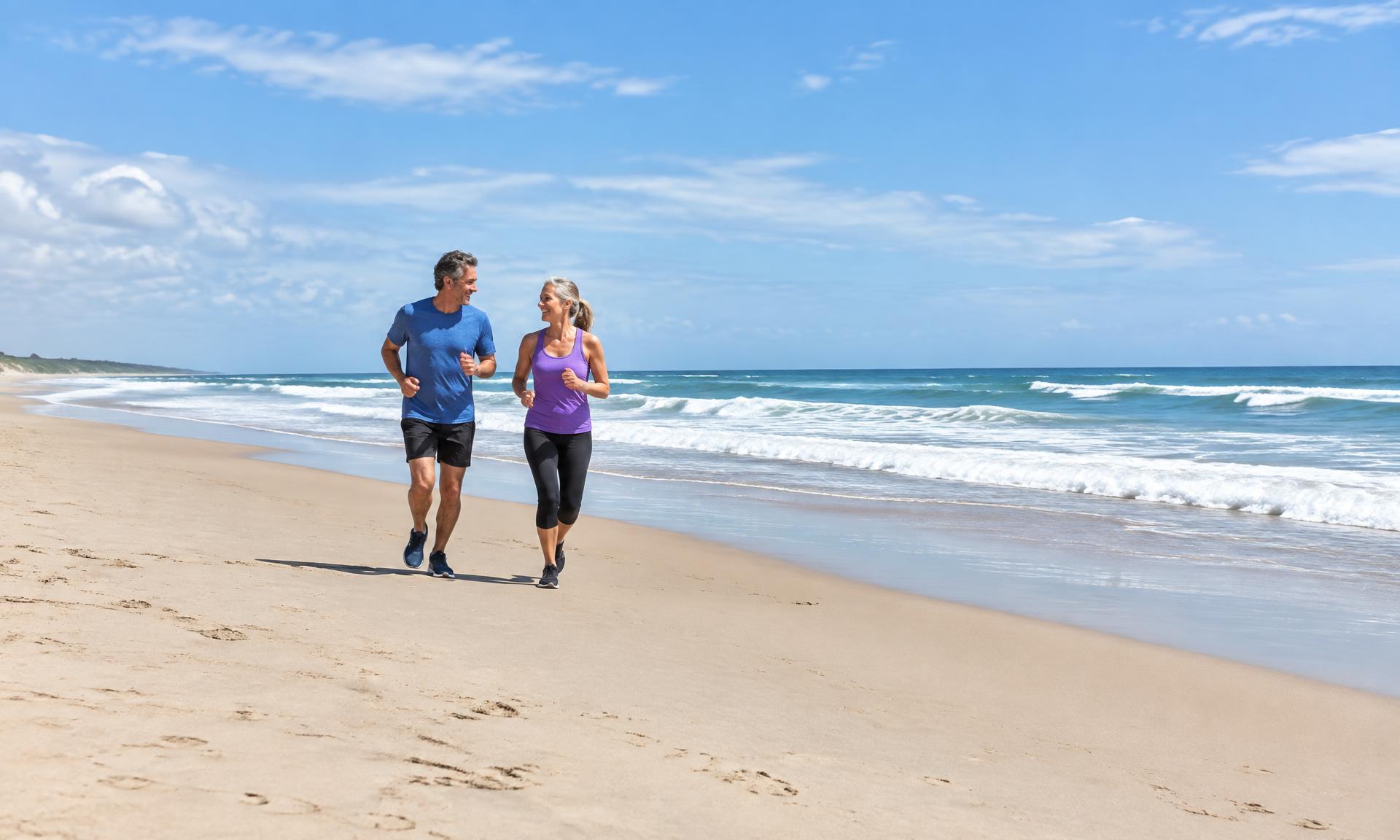 Two people over 50 jogging together on a sunny beach